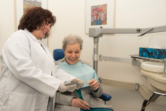 Cecilia showing example dentures to patient