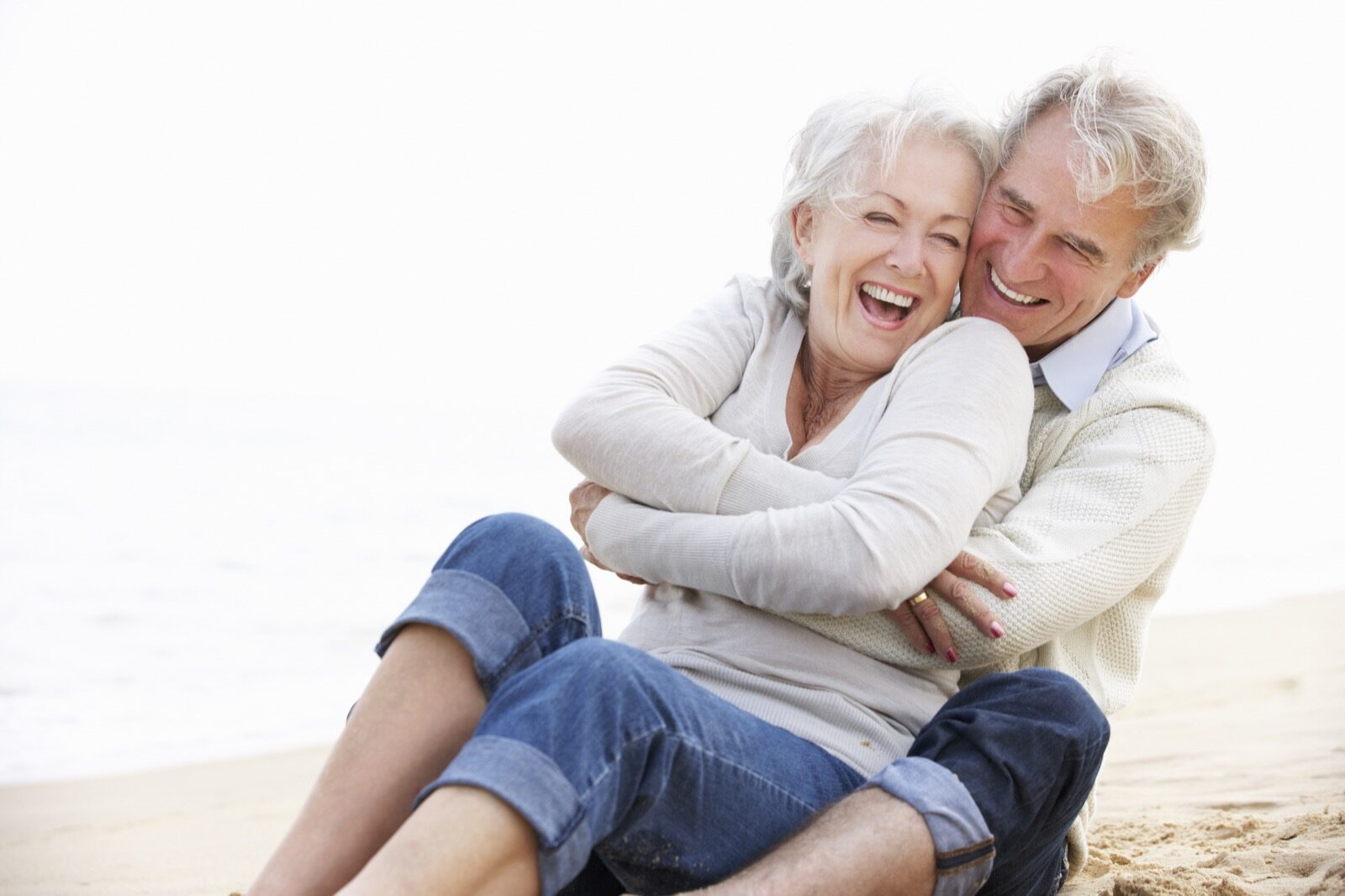 Elderly couple smiling and hugging on a beach