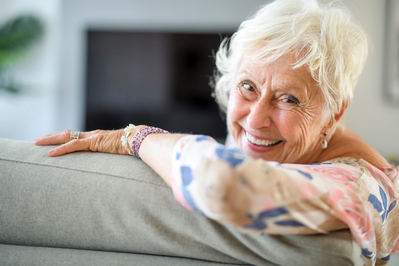 Elderly lady sitting on couch and smiling